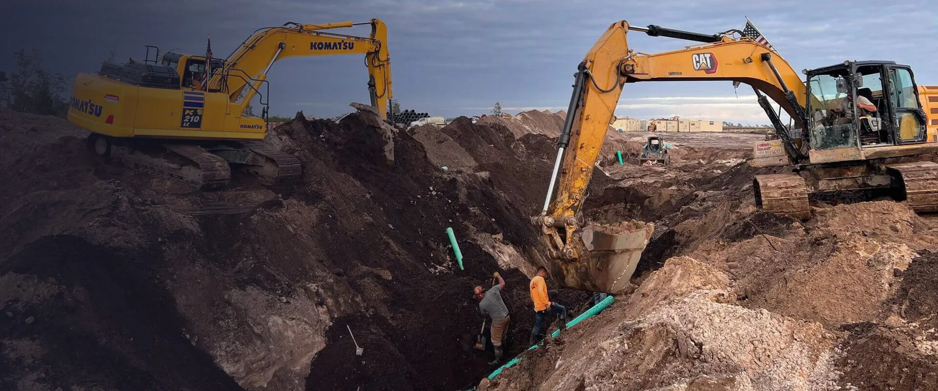 Crew installing pipe in a deep trench